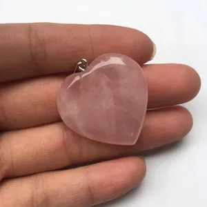 Macro view of a 25mm natural rose quartz heart pendant held in hand for detail