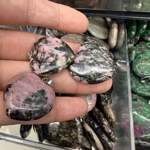 Close-up of heart-shaped natural pink rhodonite stone pendants with metal bails