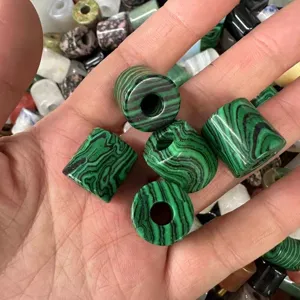 Close-up of green malachite style cylindrical stone beads held in hand for DIY jewelry