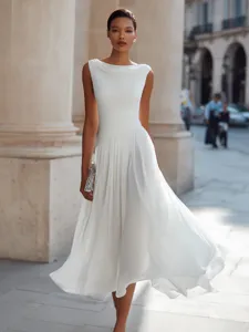 Detail view of elegant white sleeveless cowl neck midi dress in urban European street setting.