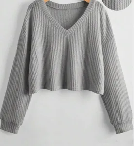 Primo piano della texture in maglia waffle grigia, dettaglio scollo a V per top casual.