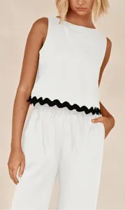 Detailed view of the elegant white sleeveless top featuring a chic black scalloped hem.