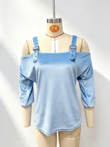 Top azzurro in velluto a maniche lunghe con spalle scoperte e dettagli di fibbia.