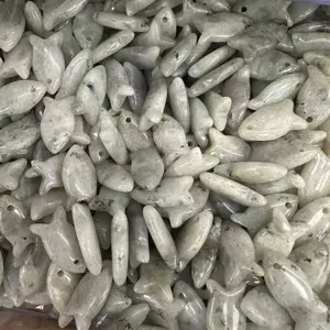 Makro-Detail von fischförmigen Natursteinanhängern mit vorgebohrten Löchern für DIY-Schmuck.
