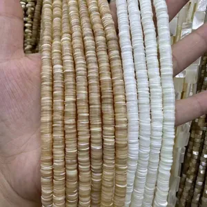 Gros plan de perles heishi en coquillage naturel 1x6 mm pour la création de bijoux DIY.
