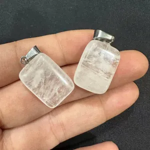 Detalle de dos colgantes rectangulares de cristal blanco natural sostenidos en la mano