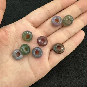 Vista macro dettagliata di perle distanziatrici in pietra naturale multicolore sulla mano