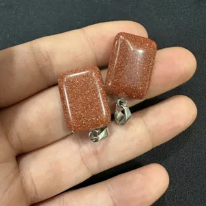 Primer plano de colgantes rectangulares de piedra de oro con destellos dorados y enganches.