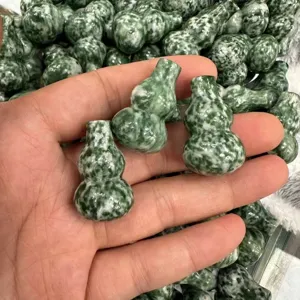 Nahaufnahme von grünen Kürbis-Anhängern aus Stein für Bastelarbeiten in der Hand.