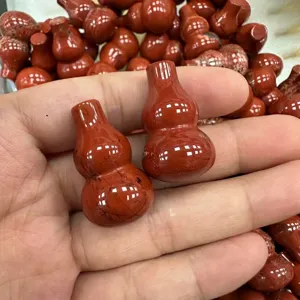 Nahaufnahme von glatten, natürlichen roten Jaspis-Stein-Kürbis-Anhängern in der Hand