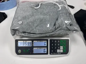 Detail view of packaged grey casual sweatpants with drawstring on electronic weighing scale.