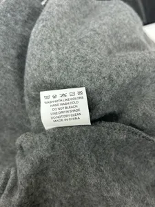 Close-up detail shot of grey fleece fabric and garment care label with wash instructions.