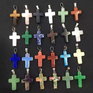 Detailed macro view of various natural stone crystal cross pendants in vibrant colors.