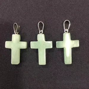 Close-up of three natural green aventurine cross pendants on black fabric background
