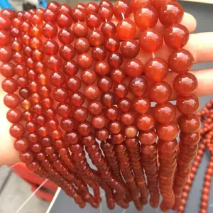 Primo piano di perle tonde in agata rossa naturale di varie dimensioni per fai da te