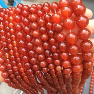 Macro primo piano di perle rotonde in agata corniola rossa naturale per la creazione di gioielli