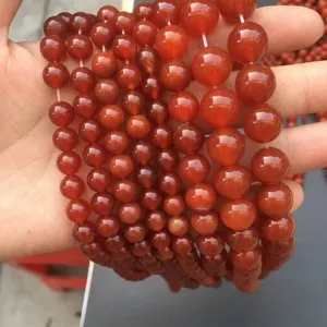 Dettaglio macro di perle tonde in agata rossa naturale di varie dimensioni per fai-da-te