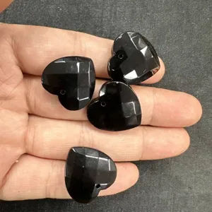 Nahaufnahme von vier 20 mm schwarzen facettierten Herzanhängern aus Stein für DIY-Schmuck.