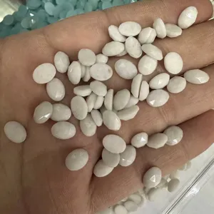Primo piano di una mano che tiene cabochon di pietra bianca ovale sfaccettata per il fai da te.