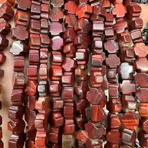Vista macro detallada de cuentas de piedra natural roja en forma de cruz para joyería DIY