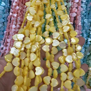 Detail view of yellow mother of pearl heart beads strings for DIY jewelry designs