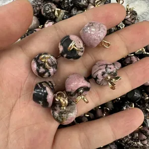 Macro view of pink and black natural stone apple pendants with elegant golden metal loops