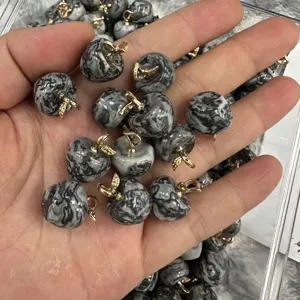 Close-up of small marbled stone apple pendants with gold leaf bails for jewelry DIY