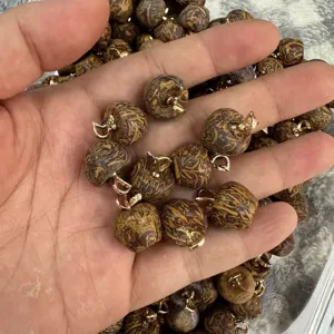 Close-up of apple-shaped natural stone pendants with brown marble texture and gold bails.