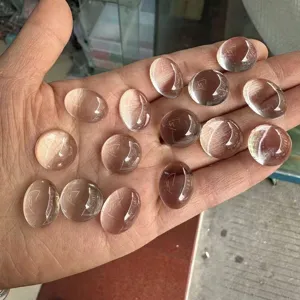Primer plano de cabujones de cristal blanco sintético ovalados y redondos en mano