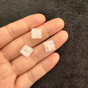 Makrodetail von drei quadratischen weißen Naturstein-Cabochons für Schmuckherstellung DIY.