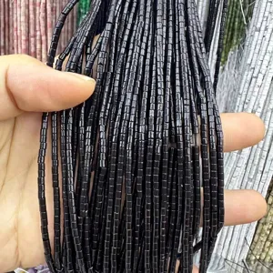 Close-up detail of 2x2mm black cylindrical natural stone beads for DIY jewelry making.