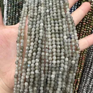 Gros plan de perles de pierre grise facettée naturelle en main