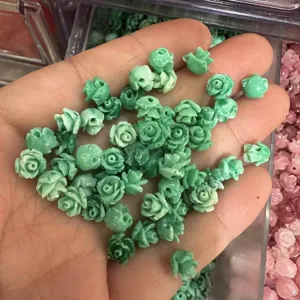 Close-up view of small green shell powder carved rose beads with horizontal holes