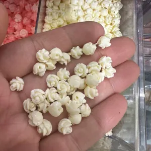 Macro detail of small cream 3D shell powder rose beads with horizontal holes for DIY jewelry