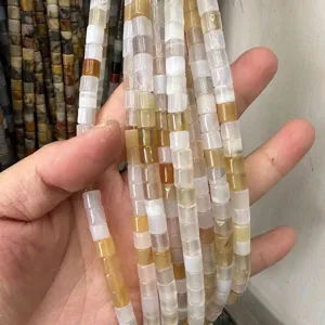 Close-up of 6x6mm cylindrical natural stone beads in beige and translucent tones