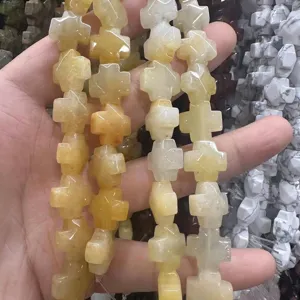 Détail en gros plan de perles en pierre d'agate naturelle en forme de croix pour bijoux.