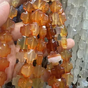 Gros plan de perles en forme de croix en agate orange pour la création de bijoux DIY.