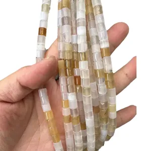 Handheld natural 6x6mm tube stone beads in earthy tan shades for DIY jewelry making