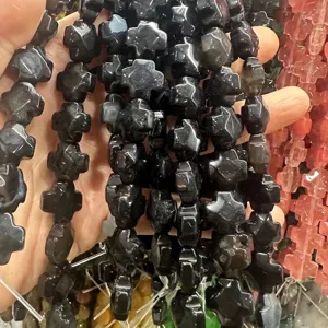 Gros plan de perles naturelles d'agate noire à facettes en forme de croix pour bijoux DIY