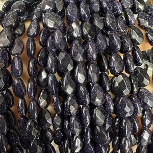 Macro shot of sparkling faceted blue goldstone flat teardrop beads for jewelry DIY