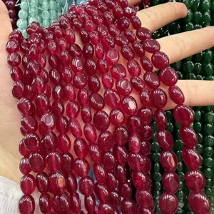 Détail macro de perles de calcédoine rubis ovales 8x10mm pour la création de bijoux DIY.