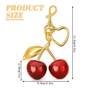 Cherry keychain detail view, gold metal and red glitter design with heart ring, size spec.