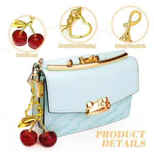 Close-up detail of light blue cherry shoulder bag, metal bow clasp and heart keyring.