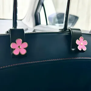 Car seat headrest hook with cute pink flower design, durable interior organizer accessory.