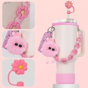 Dettaglio in primo piano della tracolla rosa intrecciata margherita e ciondolo peluche per tazza.