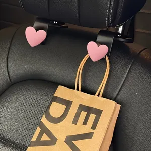 Close-up detail of cute pink heart car seat headrest hook, stylish interior organizer accessory.
