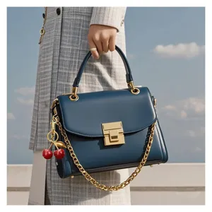 Primo piano dettagliato di una borsa blu elegante con un grazioso ciondolo a ciliegia.