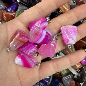 Detailed view of pink striped agate trapezoid pendants held in hand for jewelry making