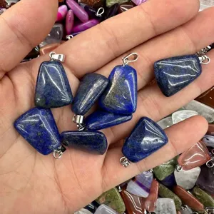 Detailed macro view of natural blue lapis lazuli trapezoidal stone pendants held in hand