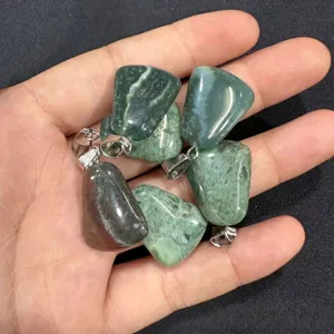 Close-up of natural green stone trapezoid pendants held in hand for jewelry making.